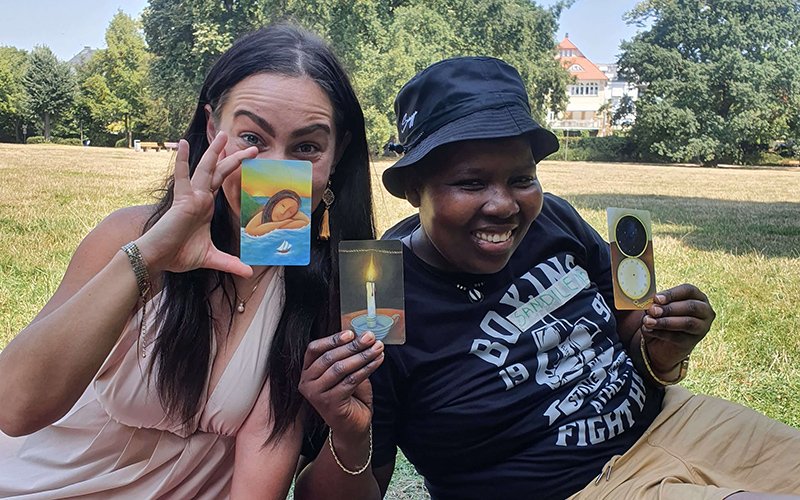 2 people smiling with cards raised showing the camera.
