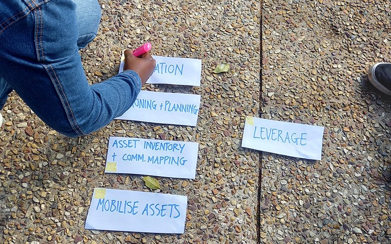 Someone writing words on small pieces of paper on the ground.