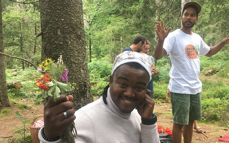 Smiling person holding up a bouquet of flowers in a forest.