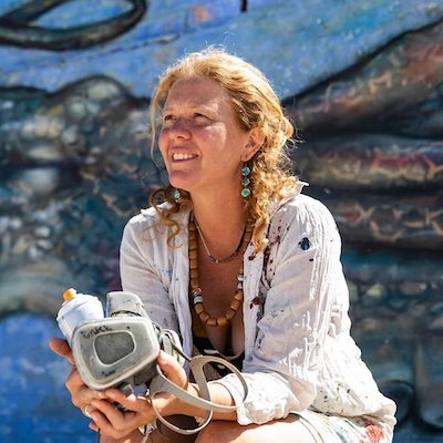 Claire Homewood kneeling with paints in her hands.